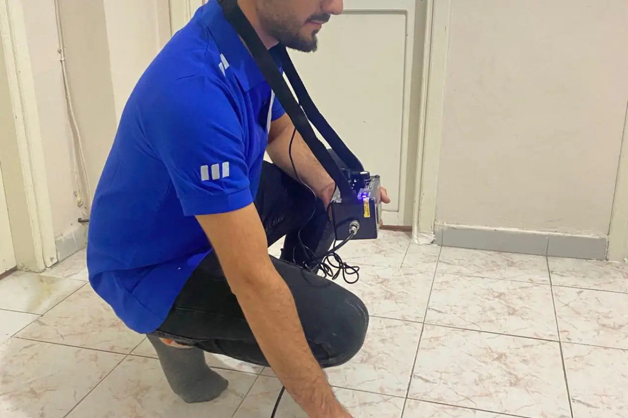 Tesisat hattını dinleme cihazıyla kontrol eden teknisyen